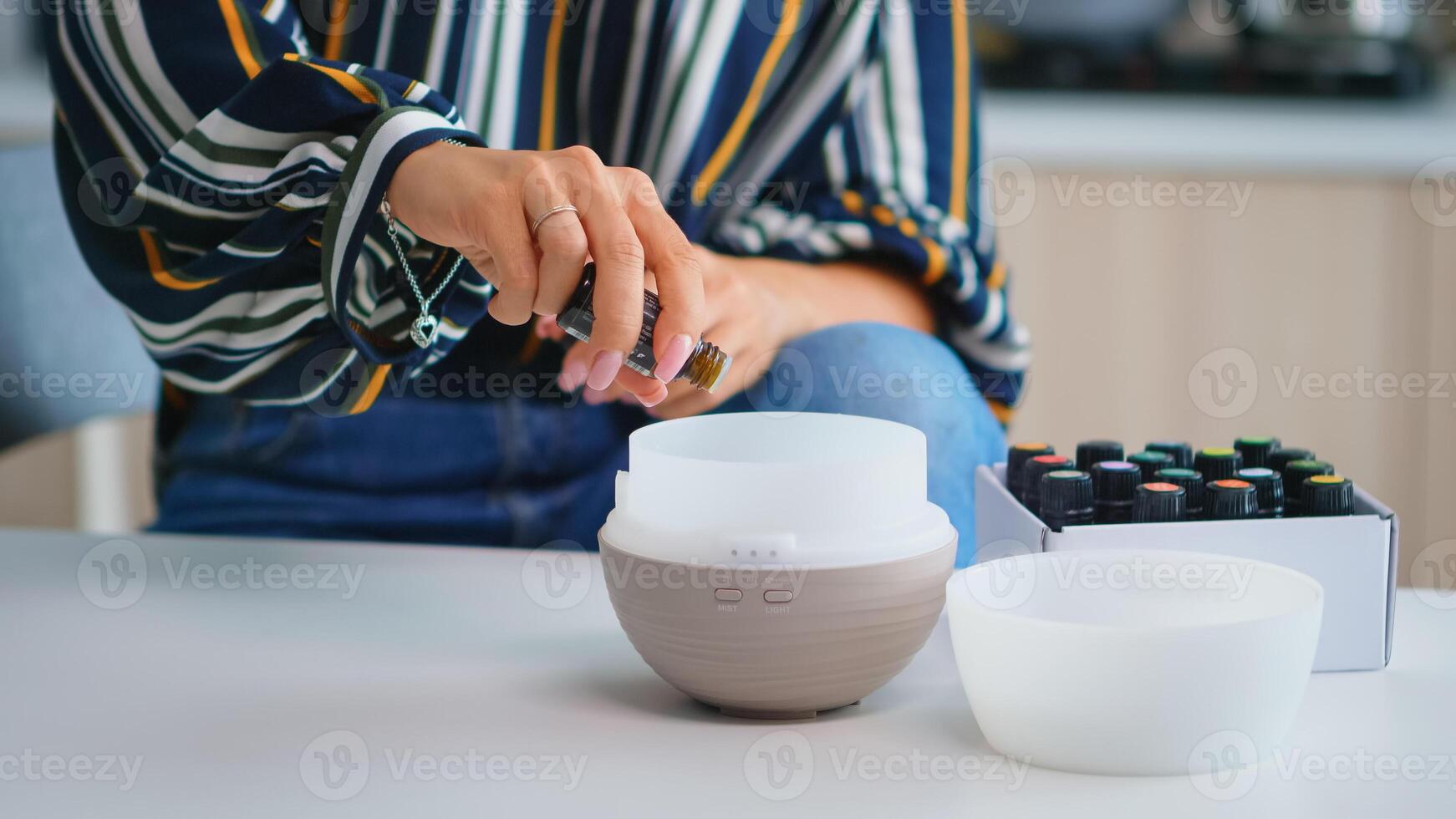 Close up of woman adding essential oils into diffuser. Aroma health essence, welness aromatherapy home spa fragrance tranquil theraphy, therapeutic steam, mental health treatment photo