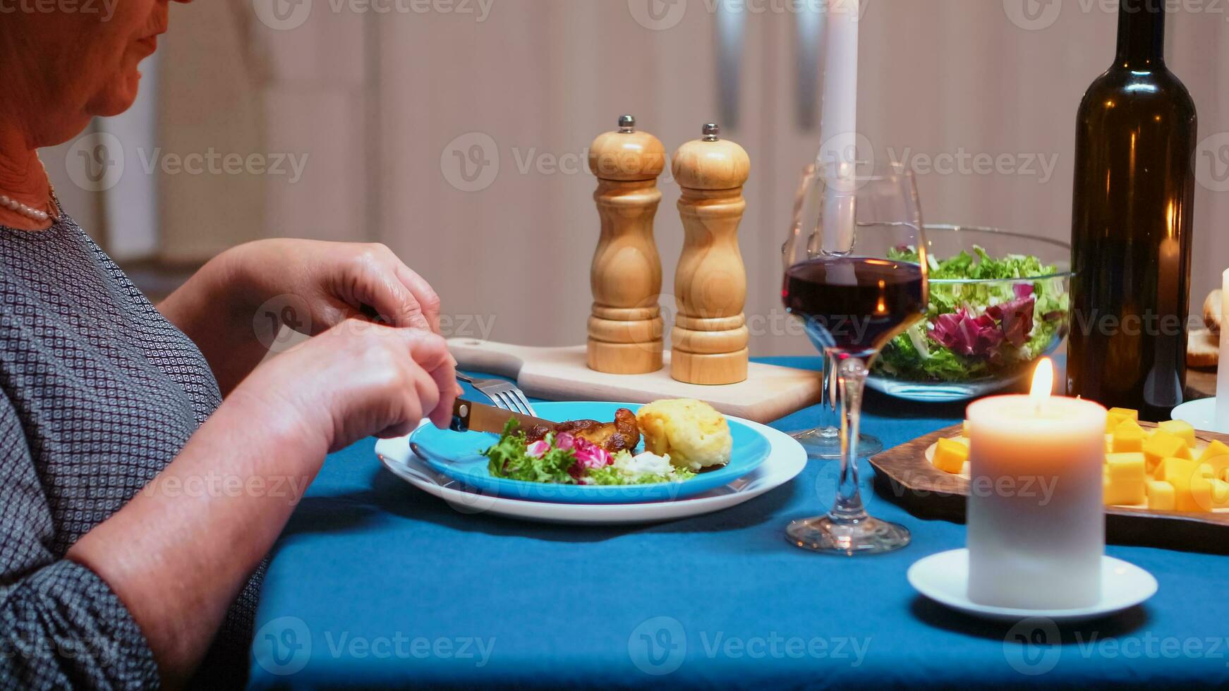 cerca arriba de comiendo saludable comida a cena, en el cocina, sentado a el mesa. mayor antiguo mujer, disfrutando el comida, celebrando su aniversario en el comida habitación foto