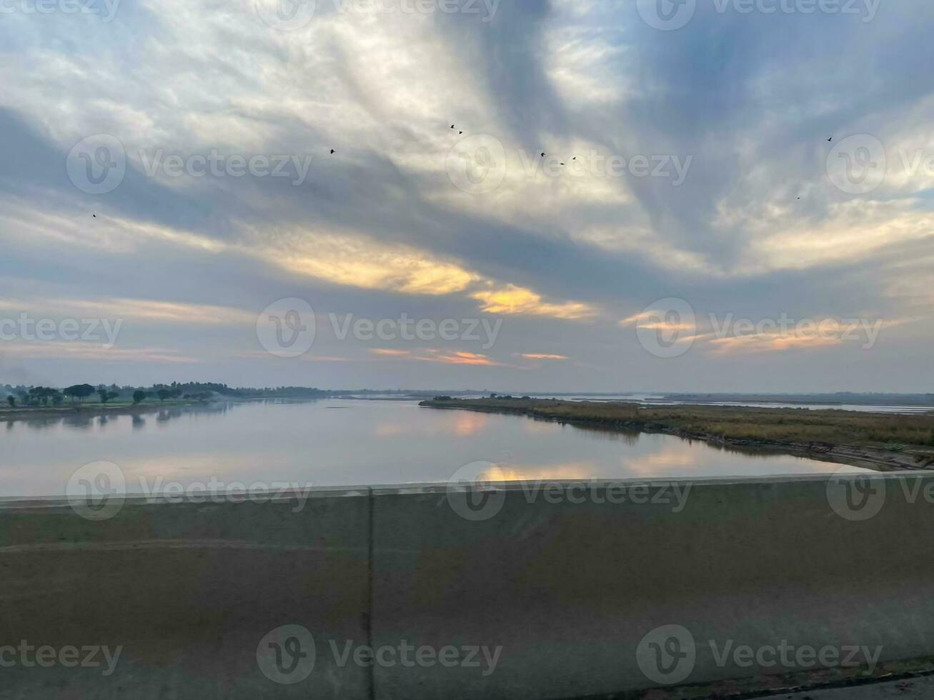 a view of the sunset from a highway over a river photo