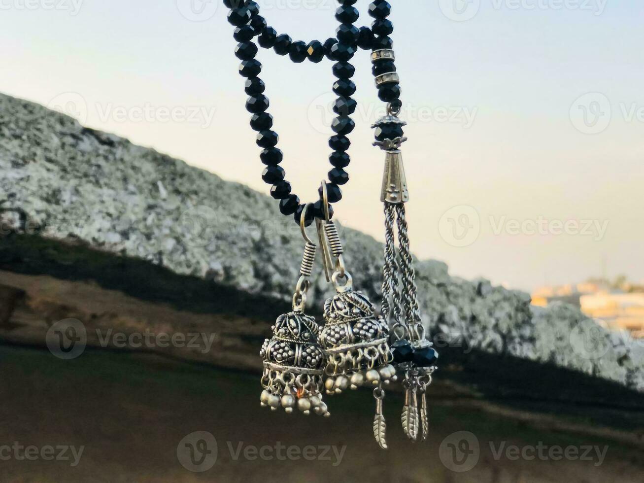 a necklace with two black beads and a silver bell hanging from a rope photo