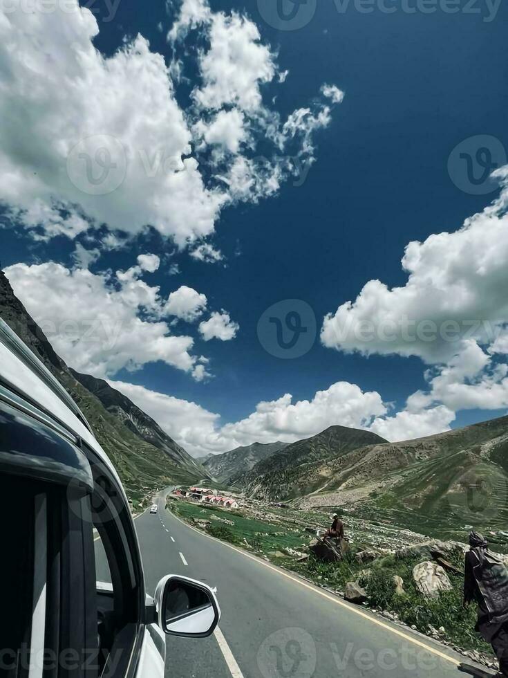 a car driving down a road with mountains in the background photo