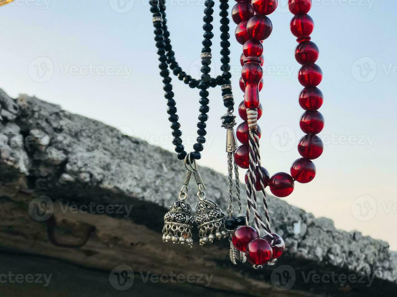 a necklace with red beads hanging from a wall photo