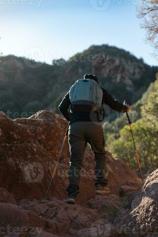 Middle-aged man climbs the mountain in the Garraf Natural Park, supported by hiking poles. photo