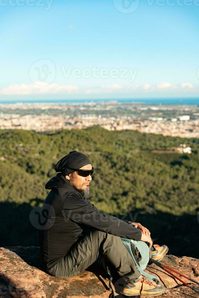 Middle-aged man contemplates the landscapes of the Garraf Natural Park while resting at the top of the mountain. photo