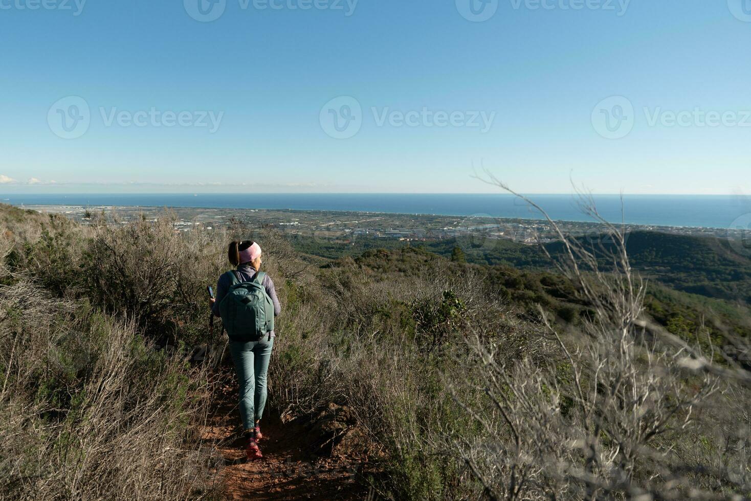 Woman contemplates the landscapes of the Garraf Natural Park while walking the paths of a mountain. photo