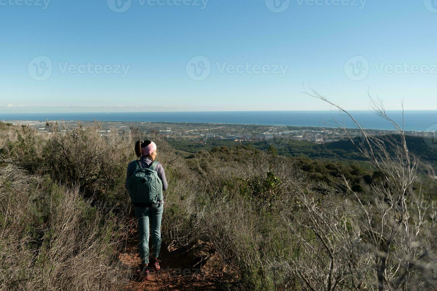 Woman contemplates the landscapes of the Garraf Natural Park while walking the paths of a mountain. photo