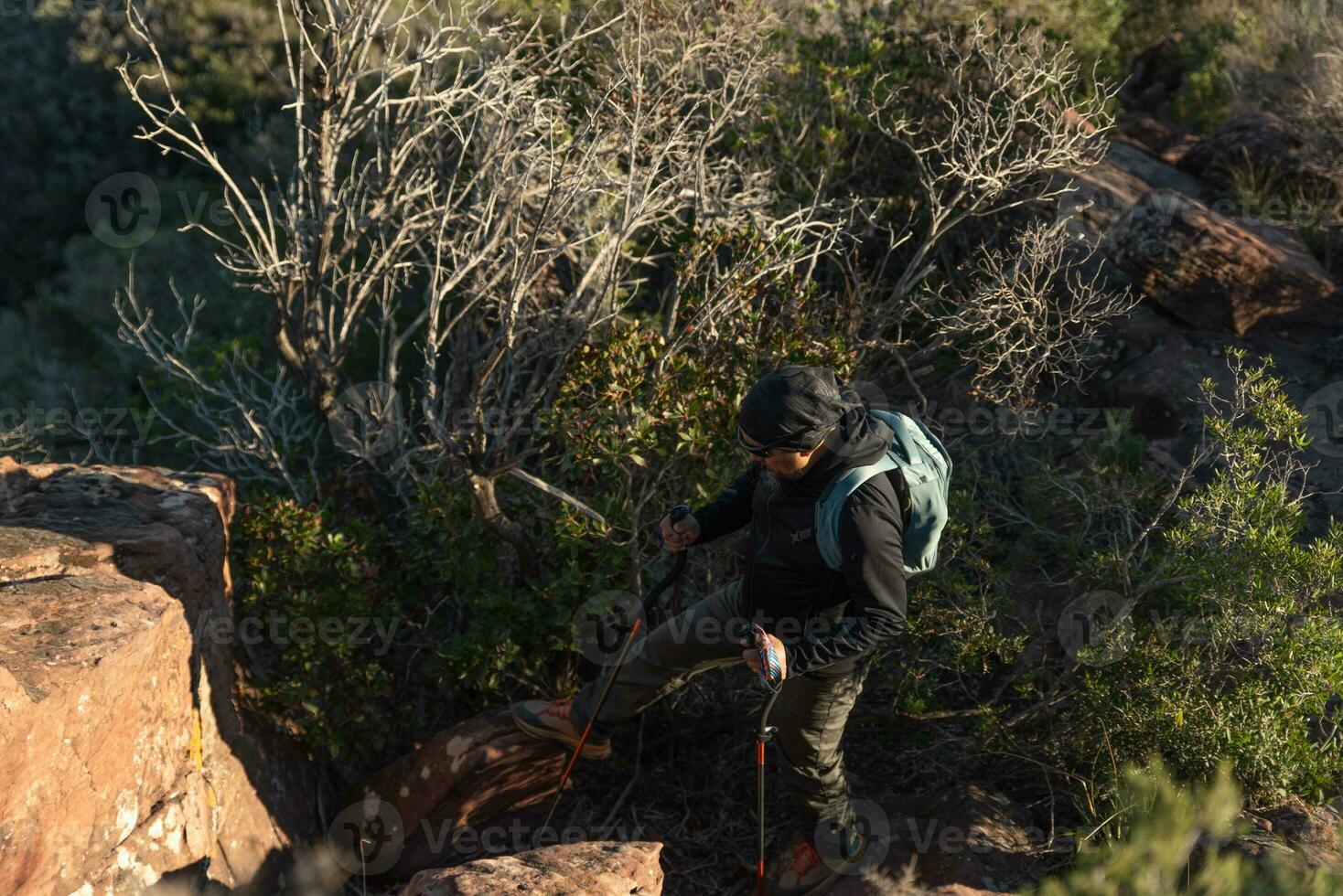 Middle-aged man climbs the mountain in the Garraf Natural Park, supported by hiking poles. photo