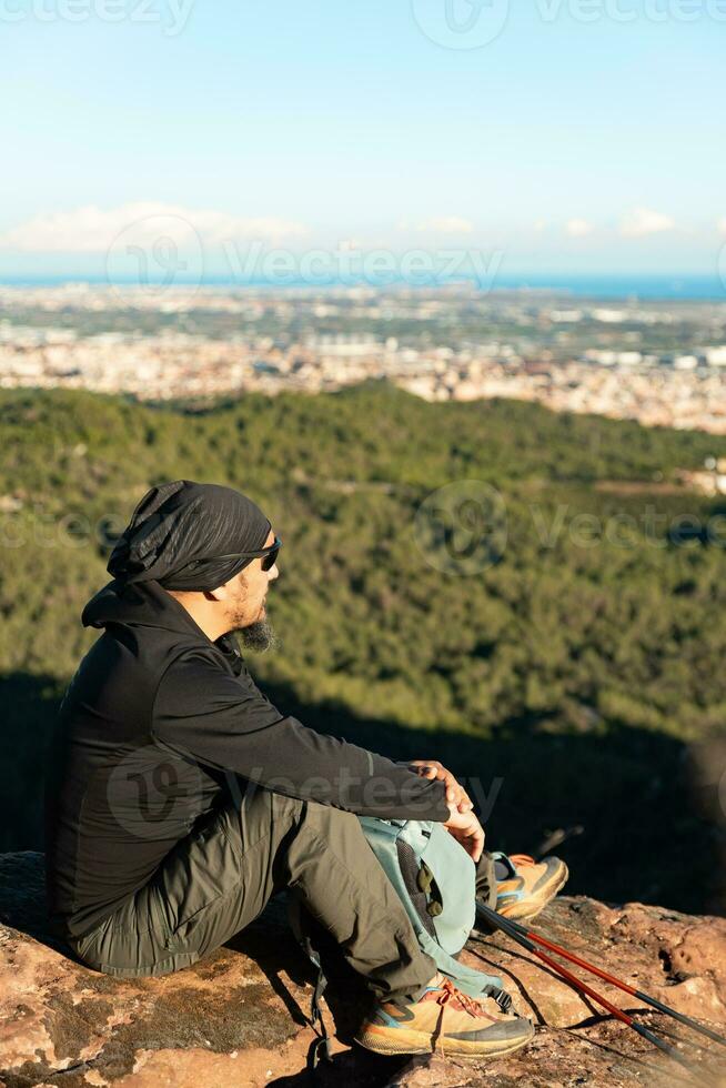 Middle-aged man contemplates the landscapes of the Garraf Natural Park while resting at the top of the mountain. photo
