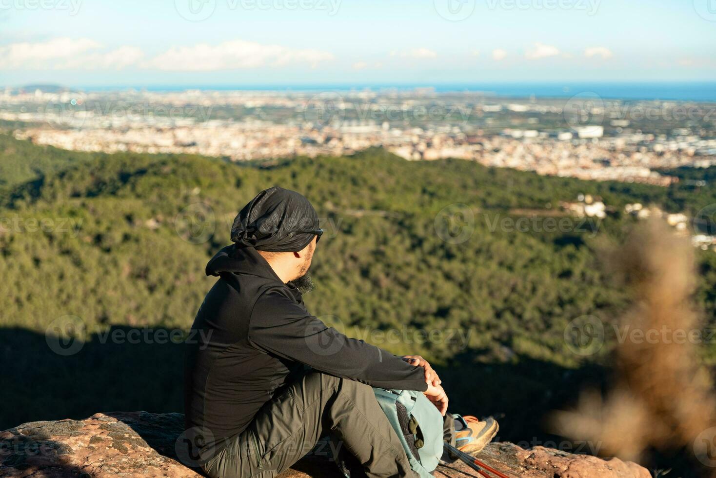 Middle-aged man contemplates the landscapes of the Garraf Natural Park while resting at the top of the mountain. photo