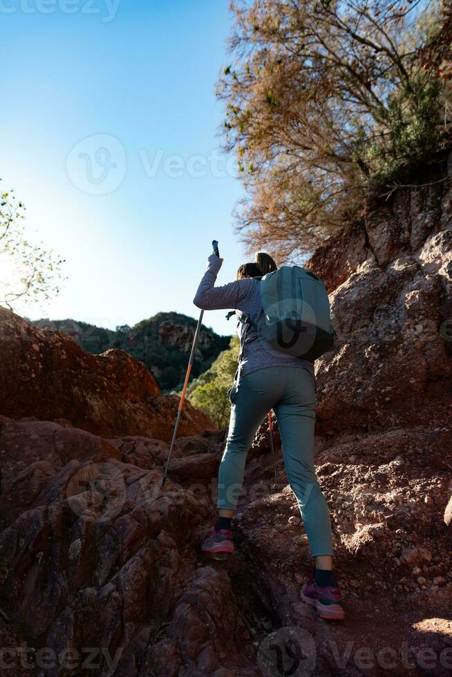 Woman climbs the mountain in the Garraf Natural Park, supported by hiking sticks. photo