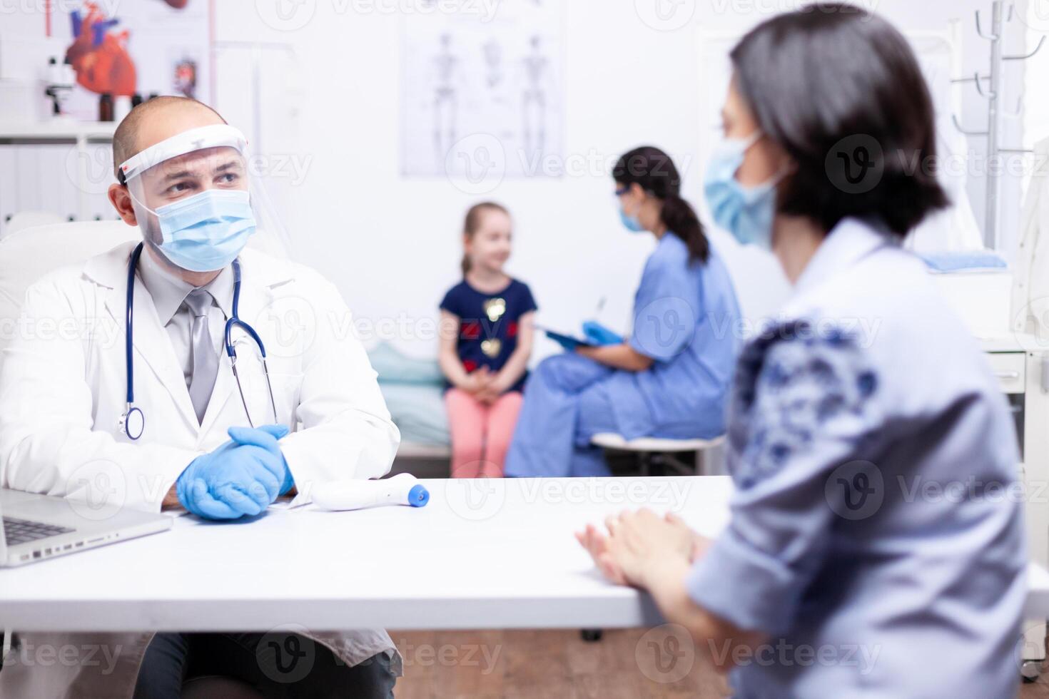 Docto having a conversation with parent while nurse consulting child wearing protection mask. Health doctor specialist providing health care services consultations treatment in protective equipment. photo