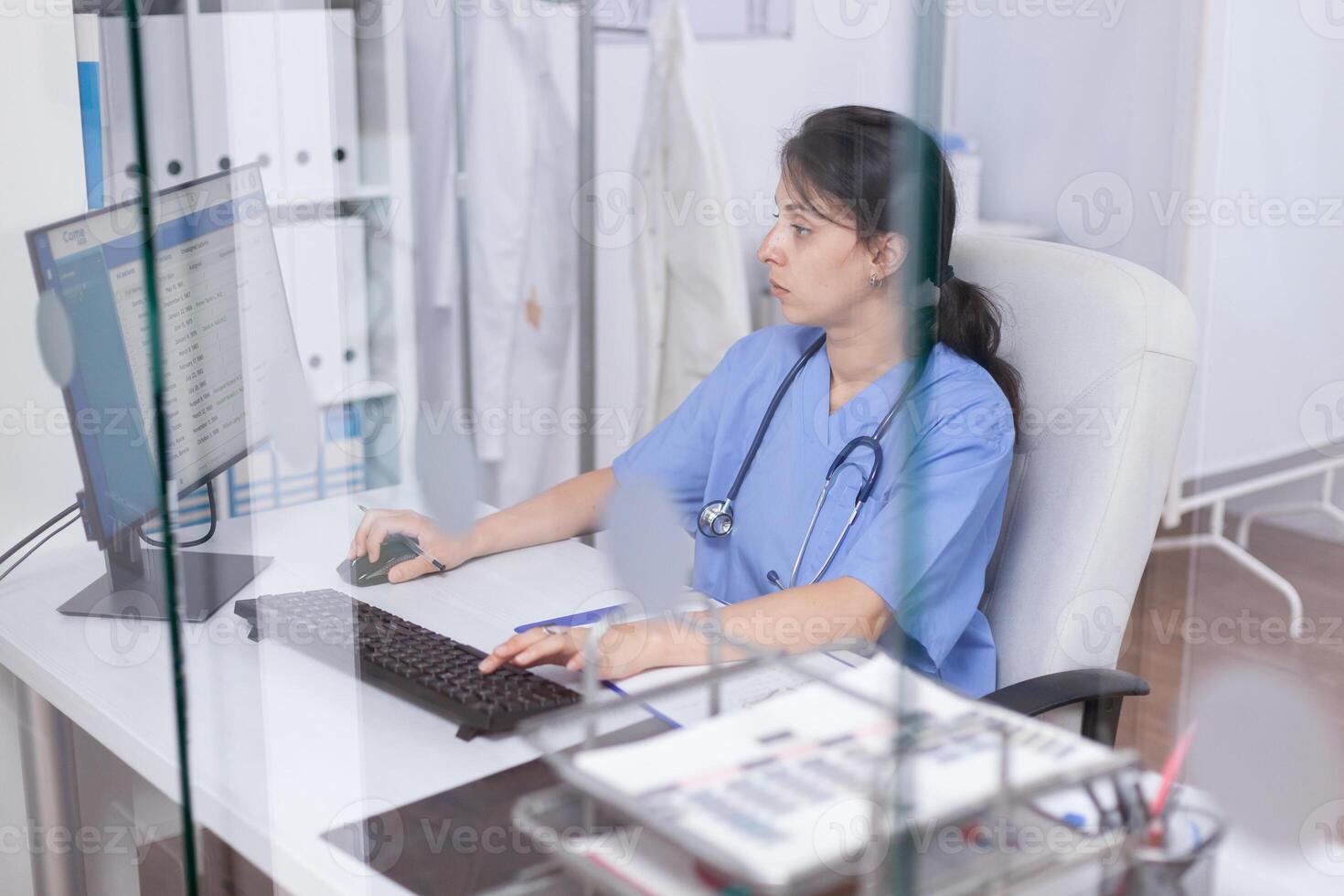 Nurse in hospital office working on computer. Healthcare physician specialist in medicine providing health care services treatment examination. photo