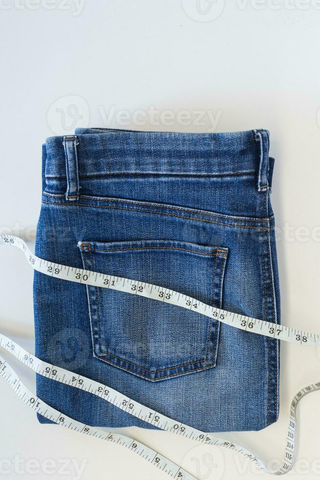 Fashion of blue jeans with measurement tape on white background with copy space. photo