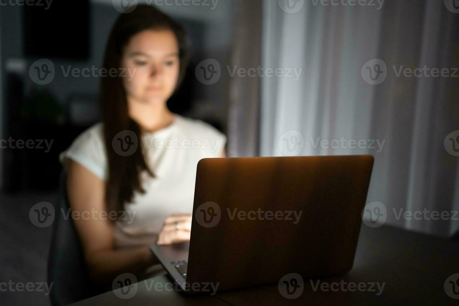 Casual beautiful woman working on a laptop at the night at home. photo