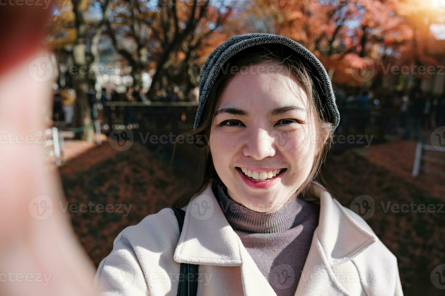 Cheerful Asian female tourist wearing a hat takes a selfie in the background in Japan photo