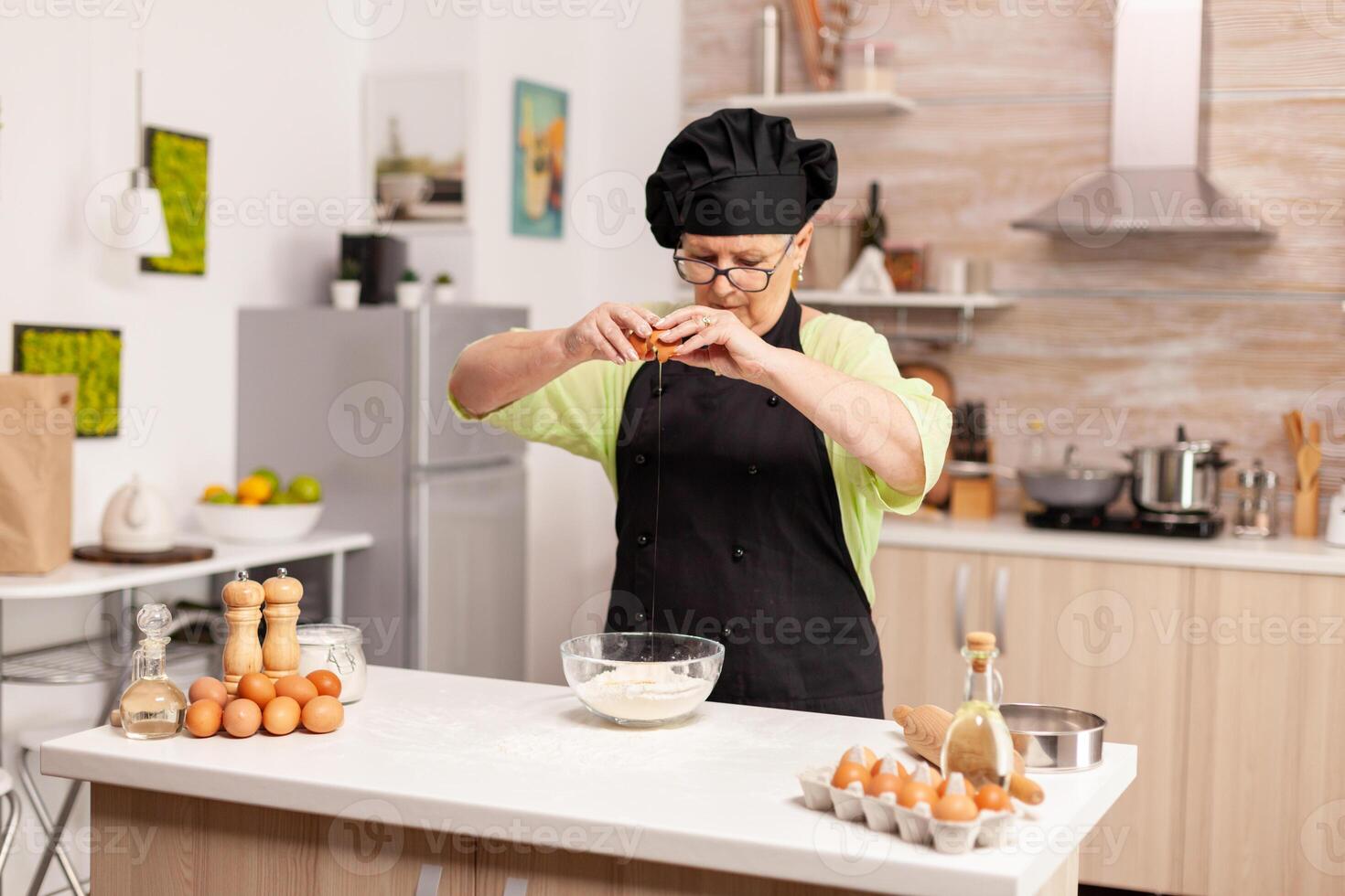 A woman prepares a dough for baking cracking eggs in home kitchen