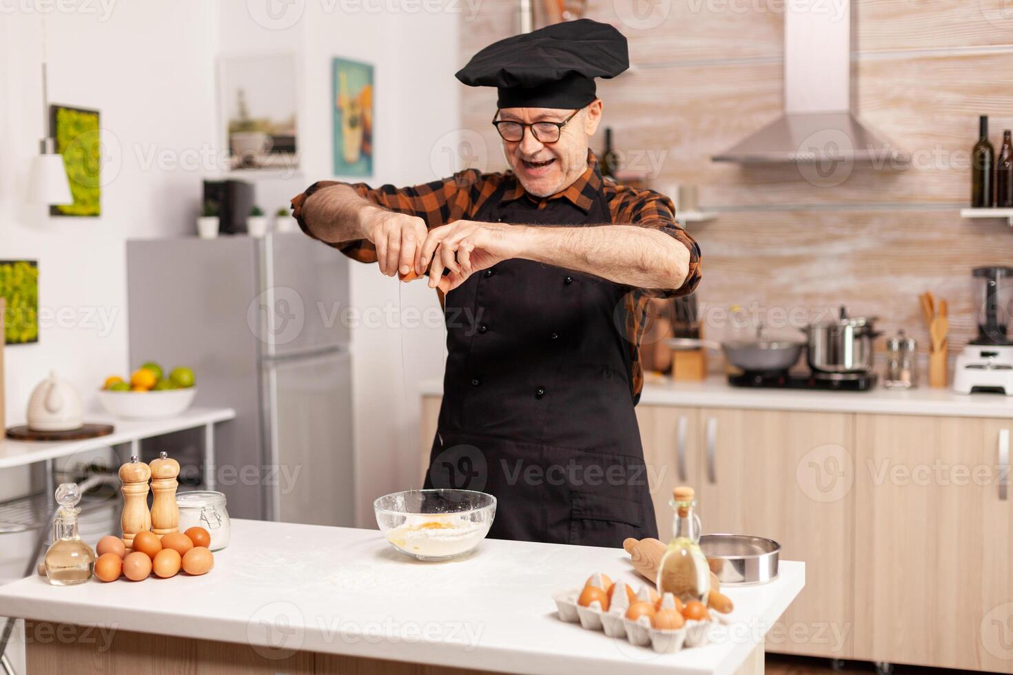 Baker preparing dough cracking eggs over wheat flour in home kitchen