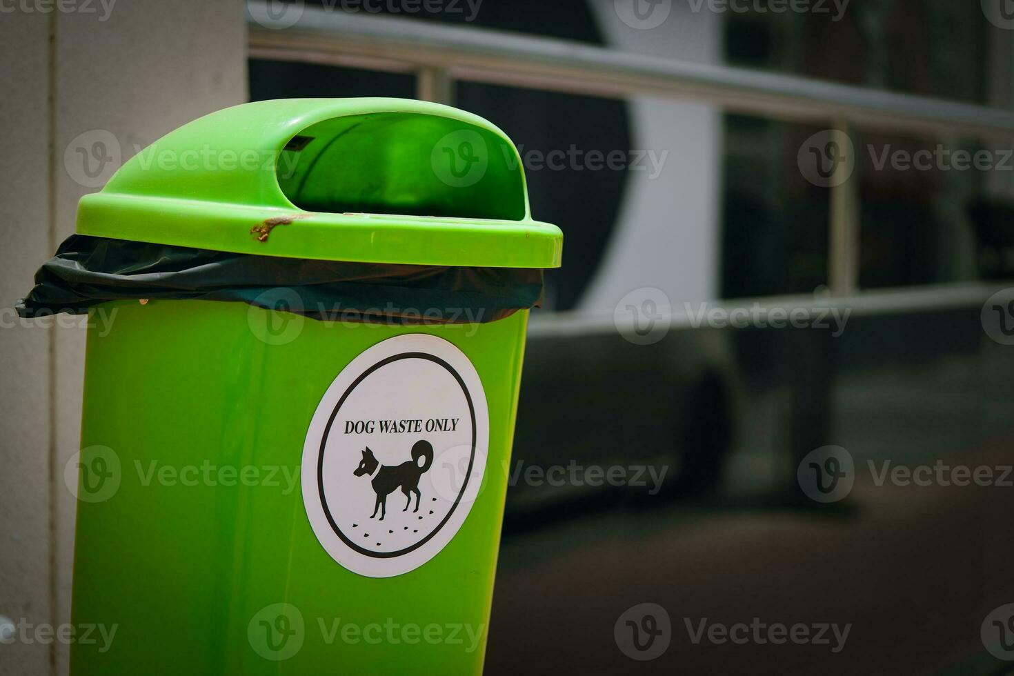 Environmentally conscious solution, this green trash bin with a white sticker to dog waste disposal, highlighting ecological mindfulness and the importance of cleaning up after dogs. photo