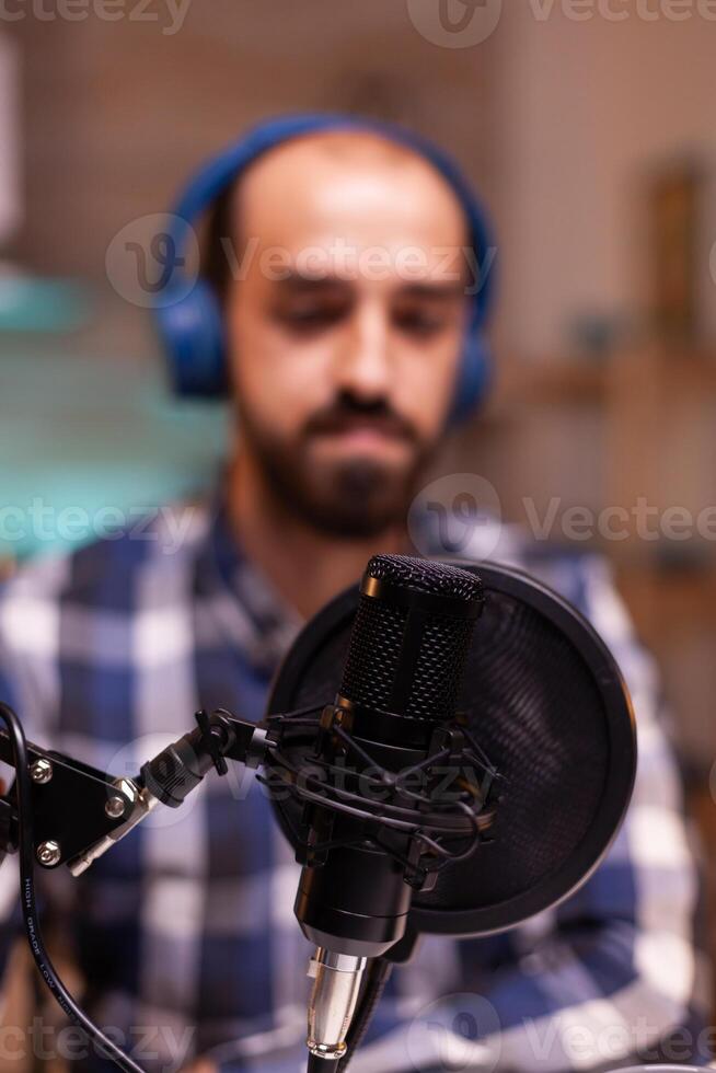 Man speaking about success in his podcast using professional recording technology in home studio. Creative online show On-air production internet broadcast host streaming live content. photo