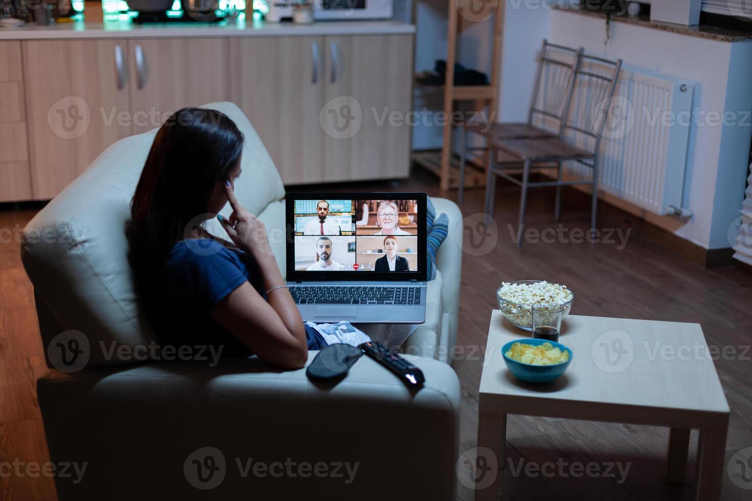 Woman speaking with colleagues on webcam lying on sofa at home. Remote worker having online meeting, video conference consulting with team using videocall working in front of laptop. photo