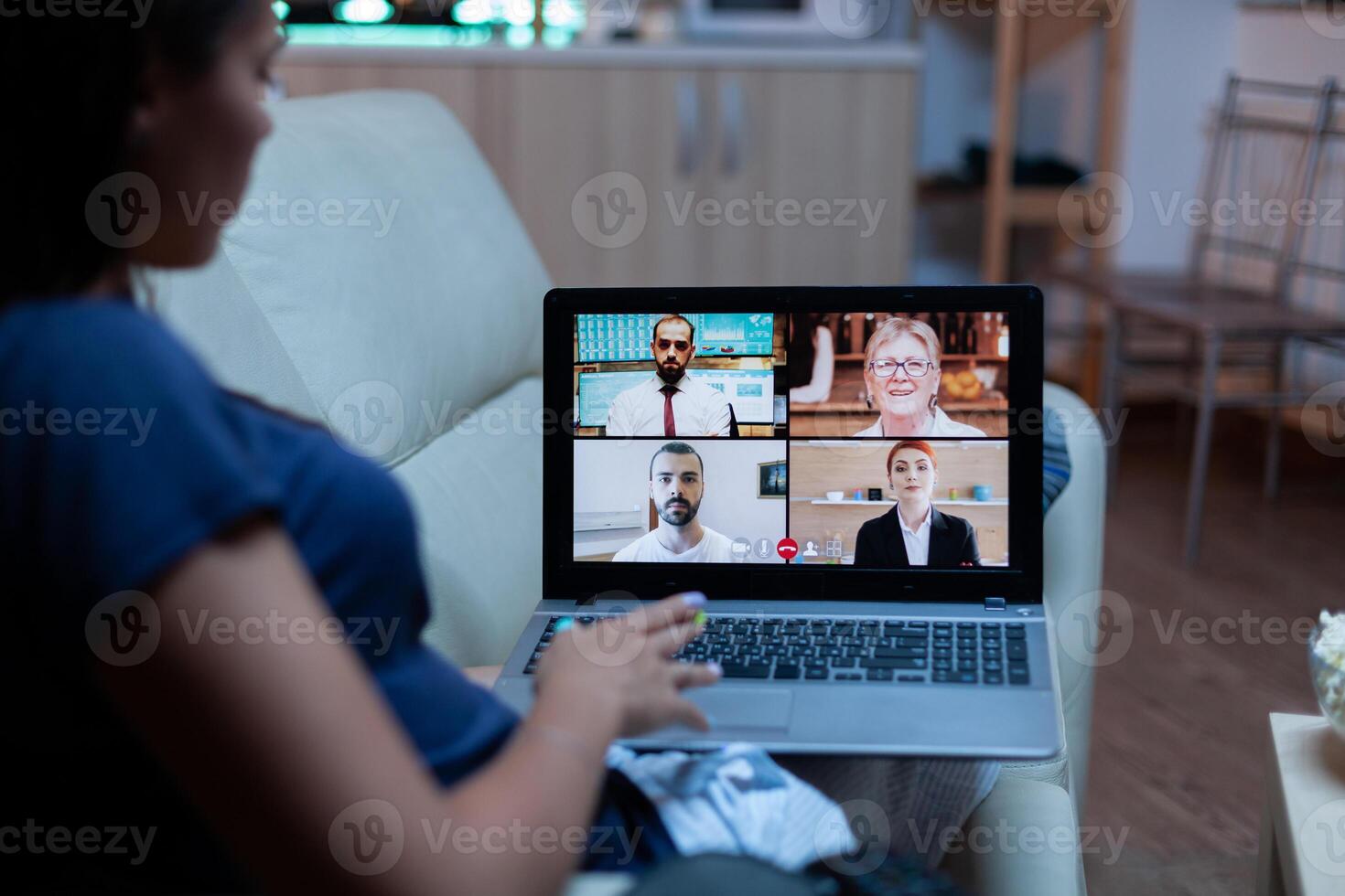 Lady in pajamas sitting on sofa having online meeting with project partners. Remote worker discussing at video conference consulting with colleagues using videocall and webcam working at laptop photo