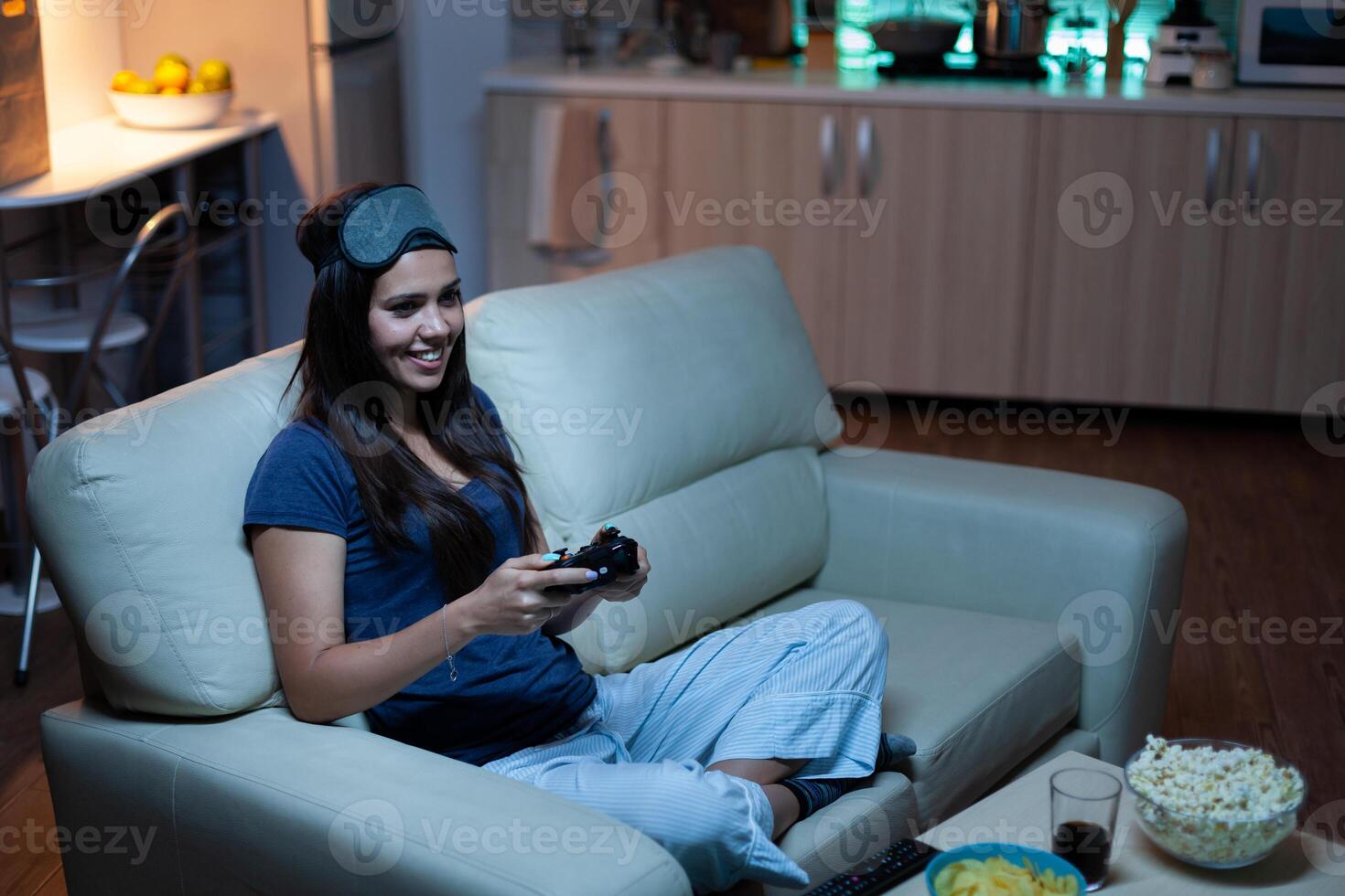 Gamer using joystick playing video games on console sitting on couch in living room. Excited determined woman using controller gamepad keypad playstation gaming and having fun winning electronic game photo