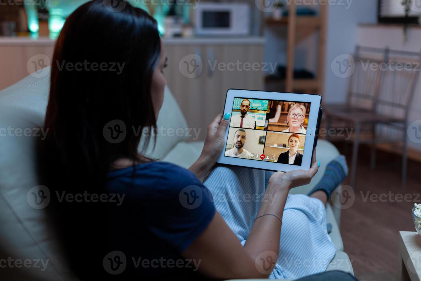 Businesswoman working from home using tablet late at night. Remote worker having online meeting consulting with colleagues on video conference and webcam chat using internet technology. photo