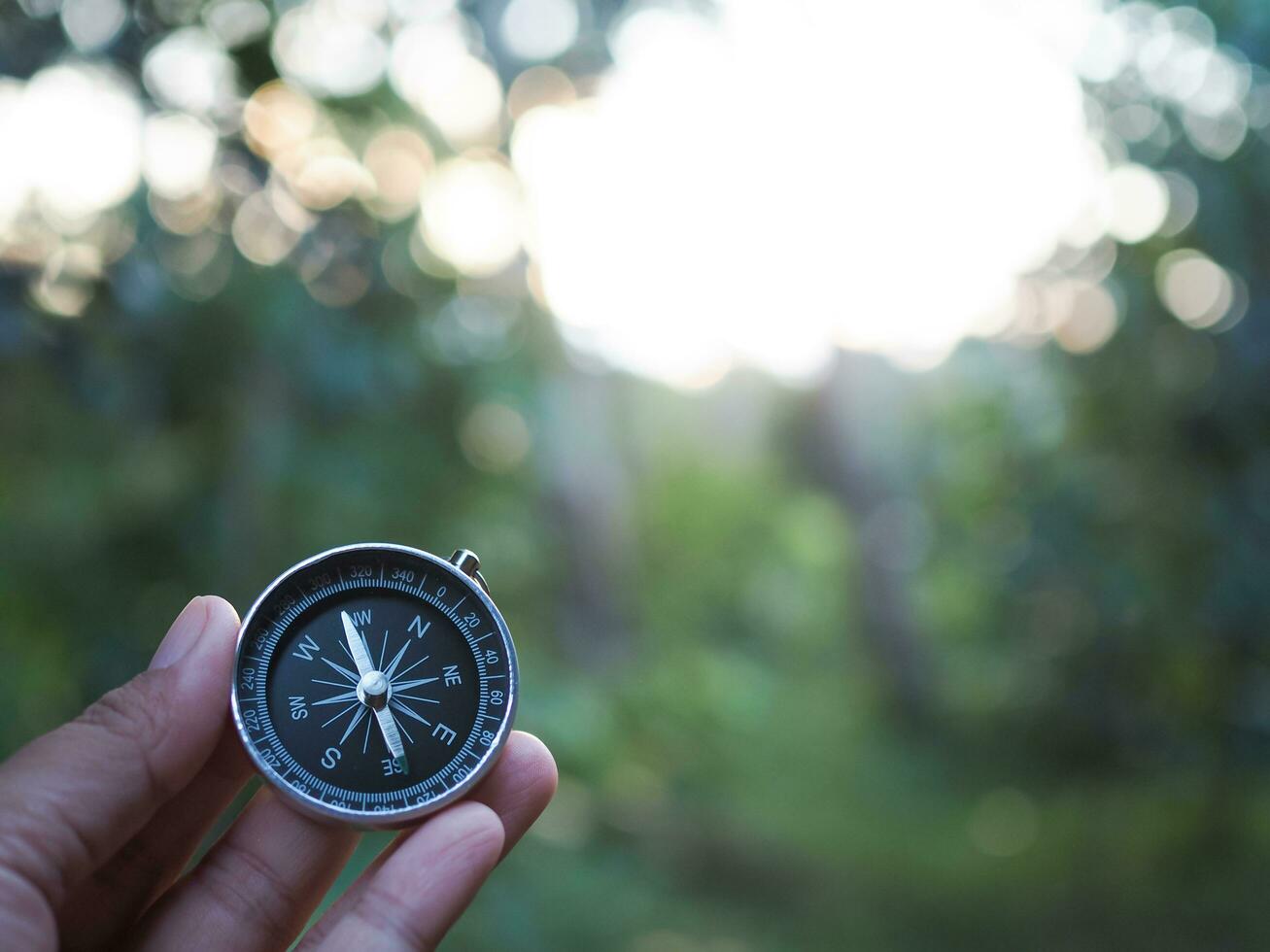 Hand holding compass with nature background. The concept of world tourism day, Searching the right directions and Travel photo