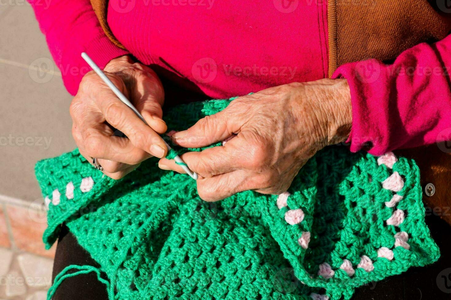 an older woman is knitting a green crocheted blanket photo