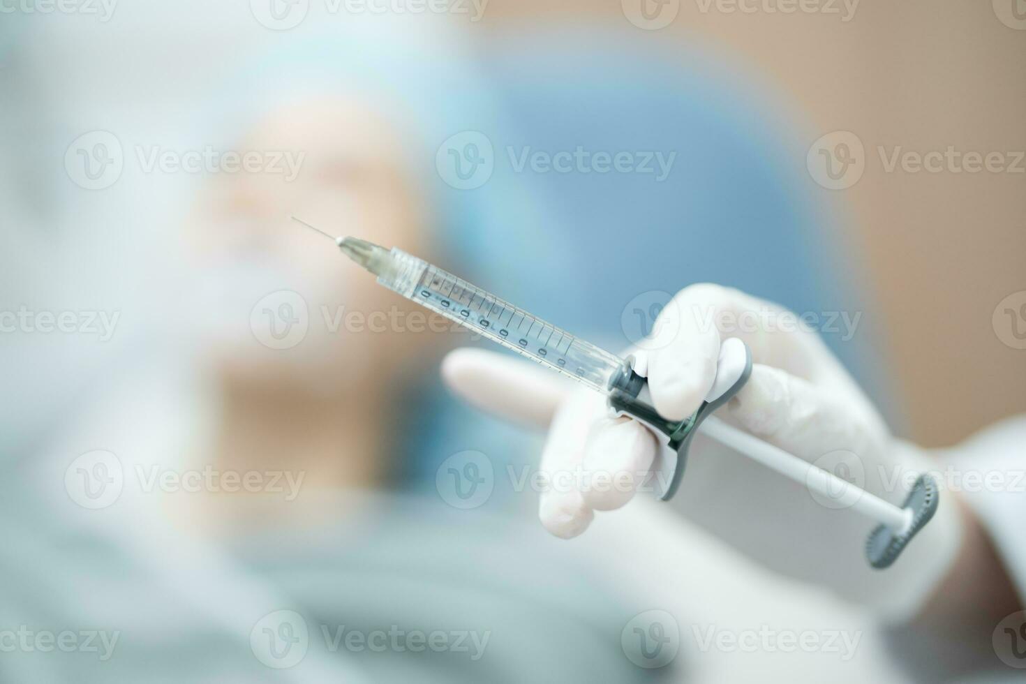 Doctor's hand in surgery glove holding syringe with needle prepare injection filler for patient. photo