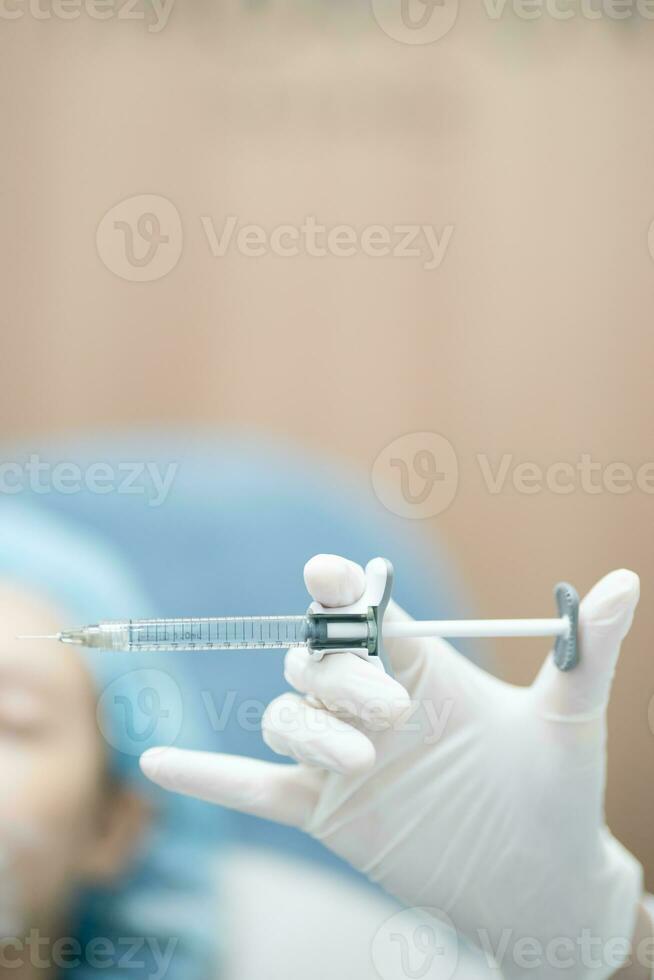 Doctor's hand in surgery glove holding syringe with needle prepare injection filler for patient. photo