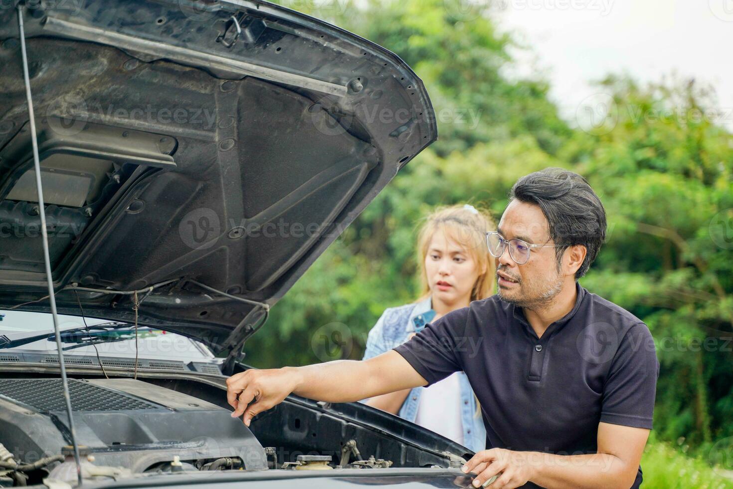 A male driver checks the condition of a car after an accident with an engine that smokes outdoor background photo
