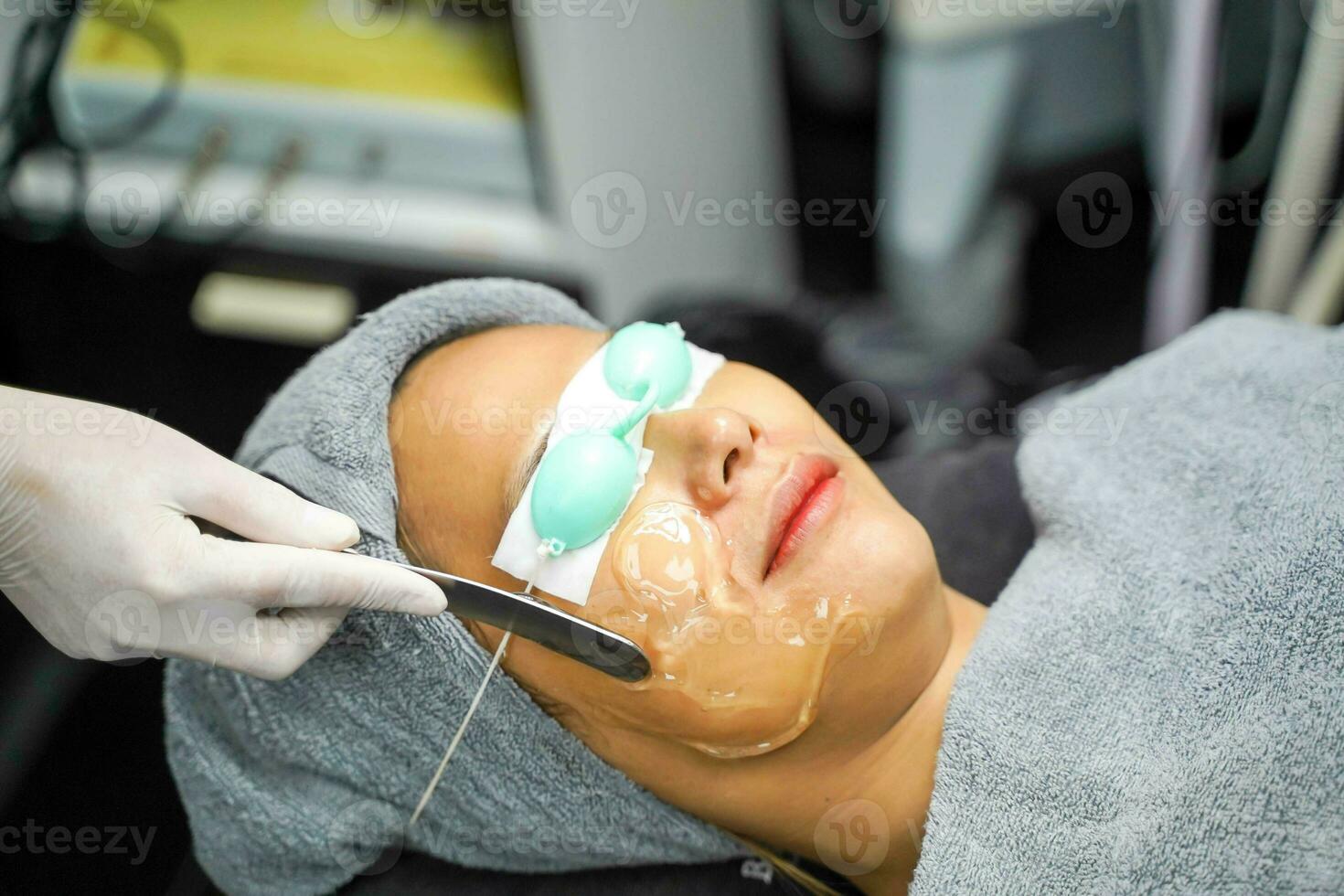 Closeup Asian beauty woman ware eyepatch and receiving skin gel to prepare the color light therapy to stimulate facial health. photo