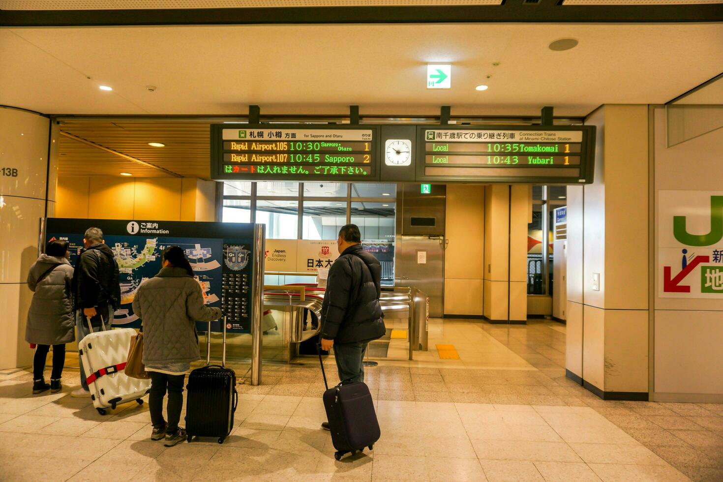 Sapporo City, Japan, 2018 - Tourists looking at area map board and local train schedule in Minami Chitose Station. photo