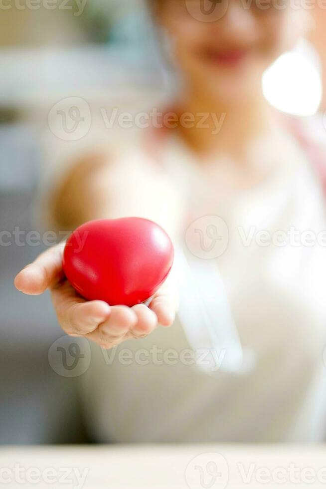 Closeup hand of medical student action give a rubber red heart on blurred background. Asian medical student with Heart disease concept. photo