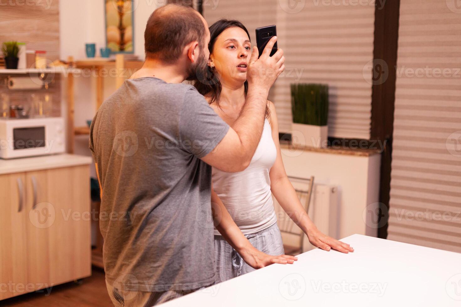 Husband having disagreement with cheating wife showing text from another man in her phone. Frustrated offended irritated accusing woman of infidelity arguing her with messages. photo