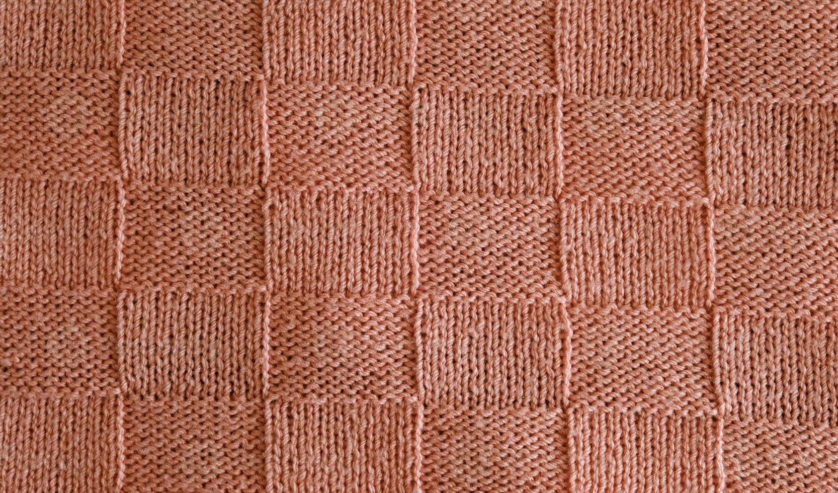 Texture of smooth knitted sweater with pattern. Top view, close-up. Handmade knitting wool or cotton fabric texture. Unusual abstract knitted chess pattern background texture. photo