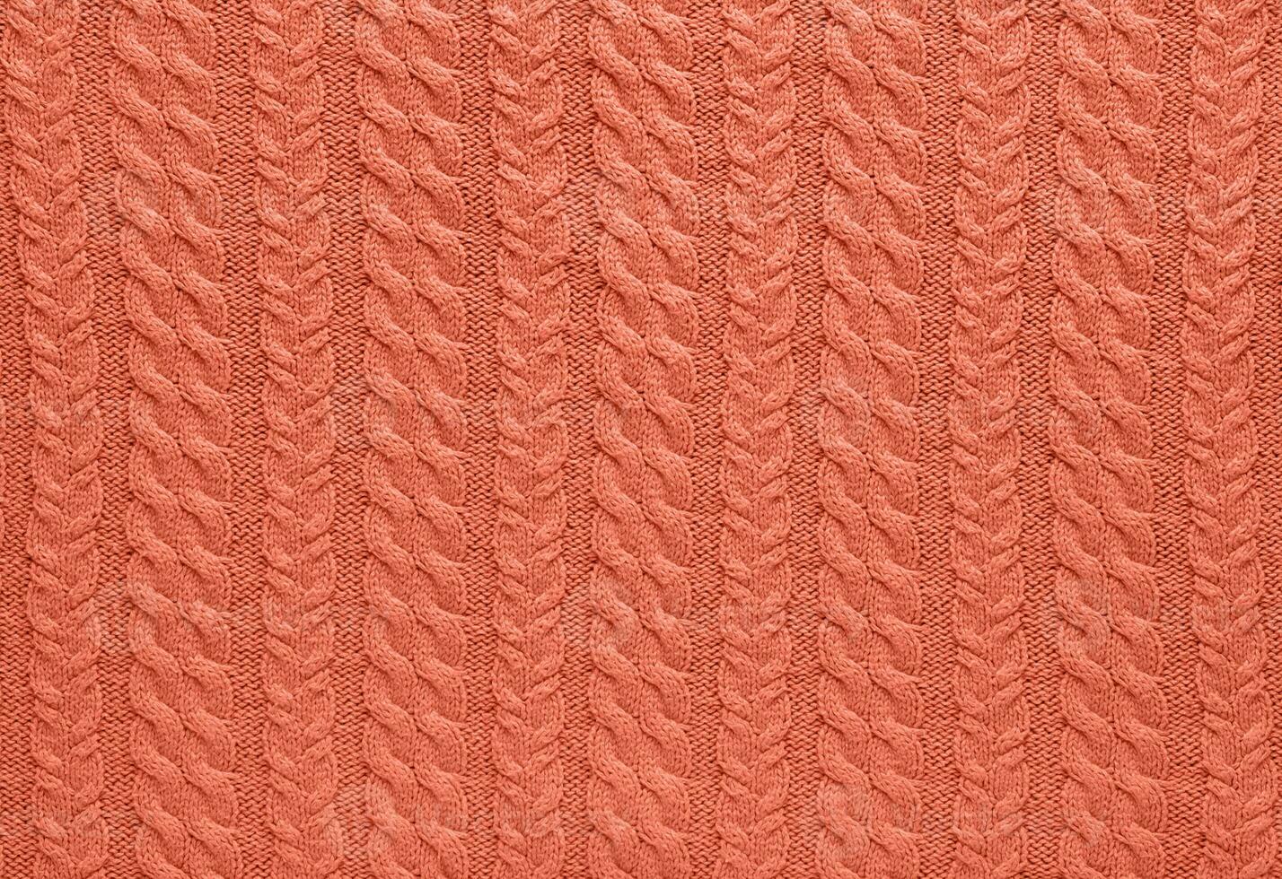 Texture of smooth knitted sweater with pattern. Handmade knitting wool or cotton fabric texture. Background of Large knit pattern with knitting needles or crochet. Peach Fuzz colour of 2024 year photo