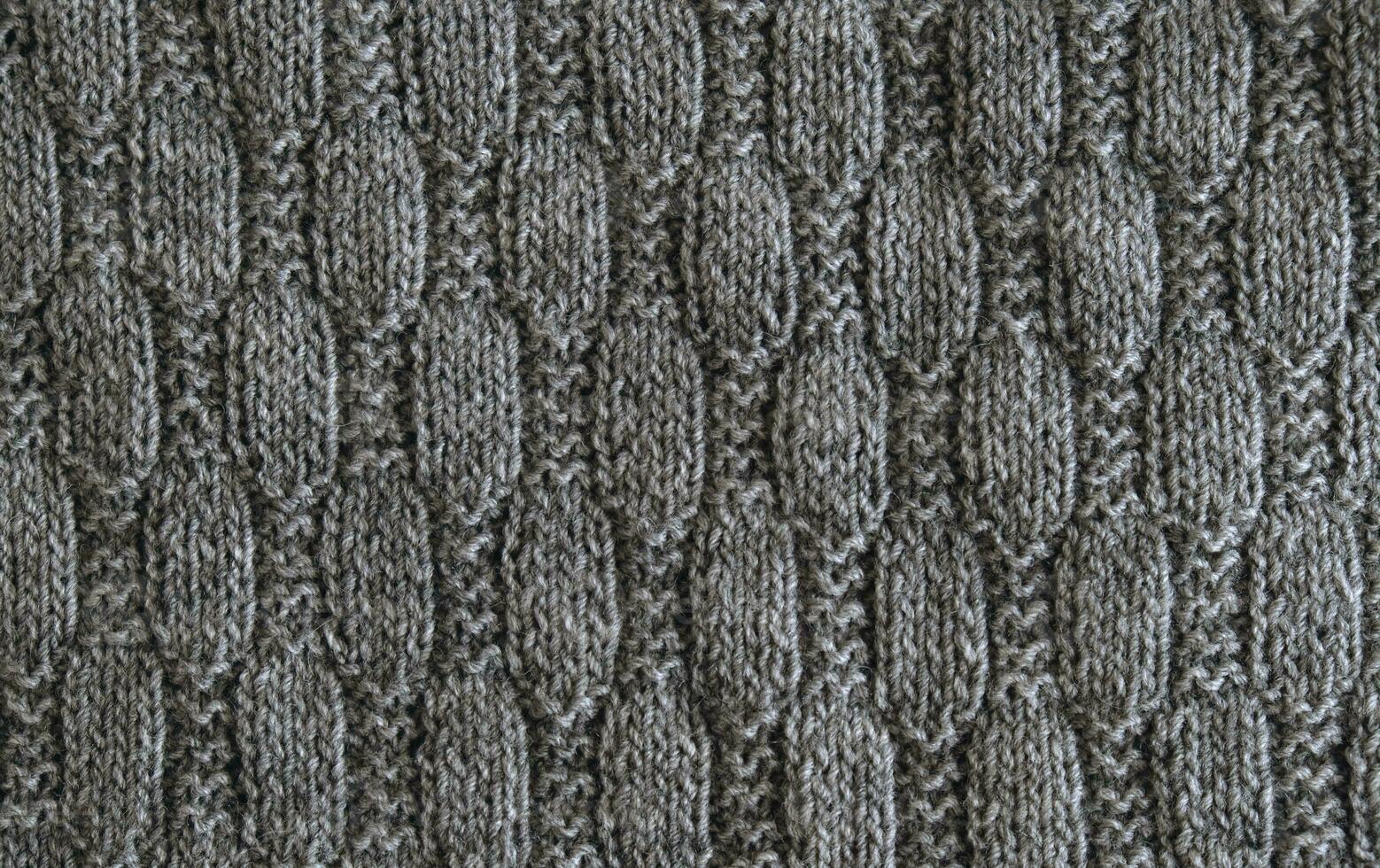 Background with gray knitted leaf shape, knitting pattern with cables. Top view, close-up. Handmade knitting wool photo