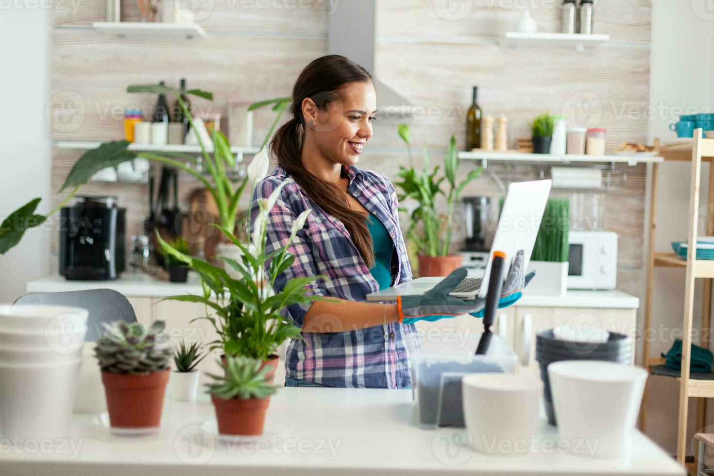 florista participación ordenador portátil en cocina mientras haciendo flores para decoración con fértil suelo. decorativo, plantas, creciente, estilo de vida, diseño, botánica, suciedad, doméstico, pasatiempo, siembra, contento. foto