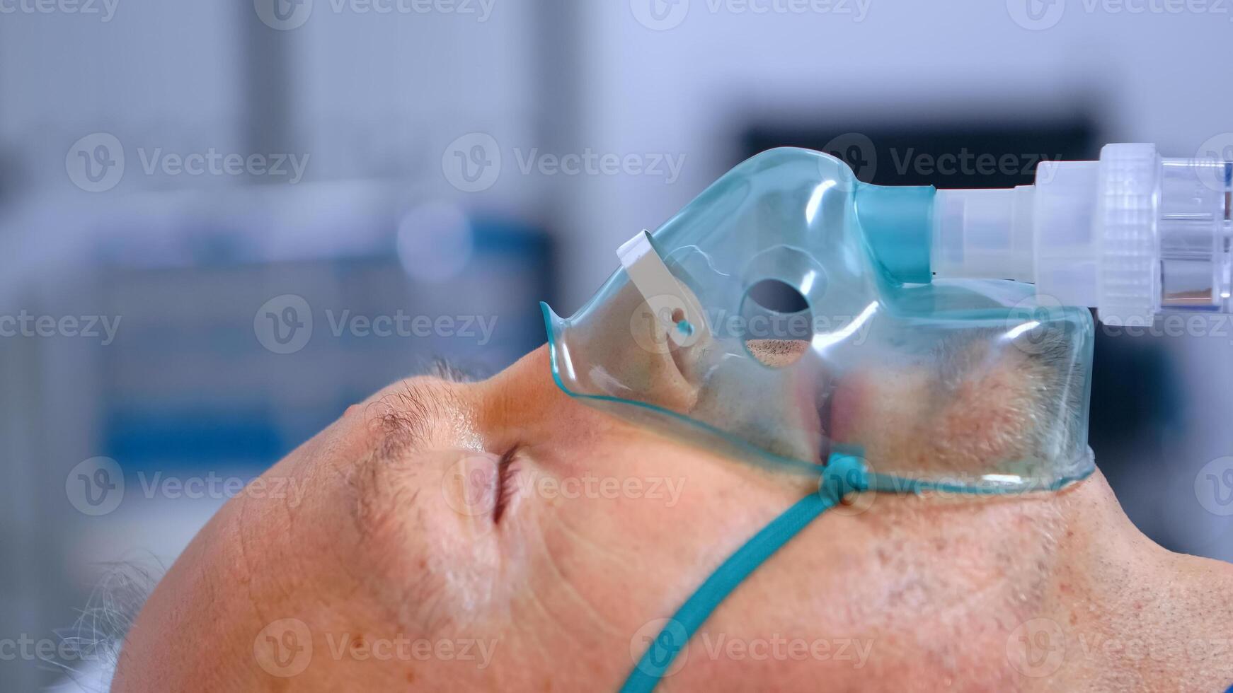 Close up of old man breathing with difficulties while wearing a respiratory oxygen mask. Coronavirus covid-19 healthcare crisis global pandemic, getting help to fight respiratory infection in modern hospital photo