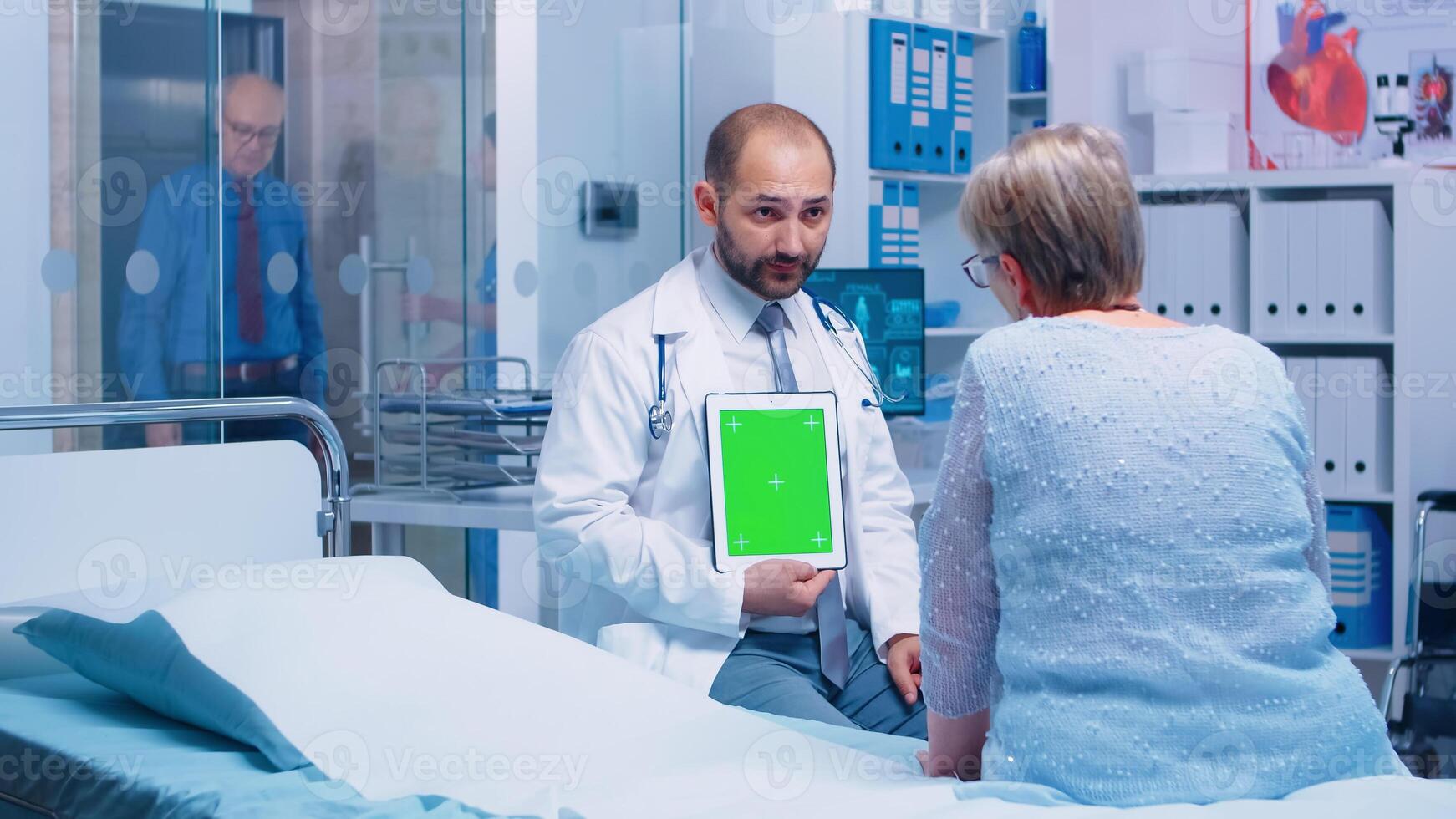 médico participación un verde pantalla tableta con aislado Bosquejo en frente de mayor paciente en un privado moderno hospital o clínica. Listo croma Bosquejo para tu aplicación, texto, vídeo o otro digital activo foto