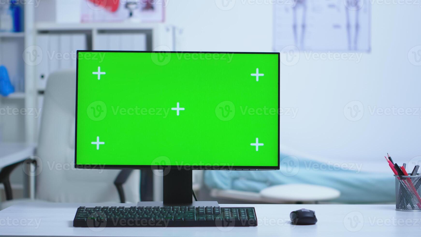 Computer desktop with green screen in hospital and specialist doctor in the background. Desktop with repleceable screen used by medicine specialist in hospital and wearing uniform. photo