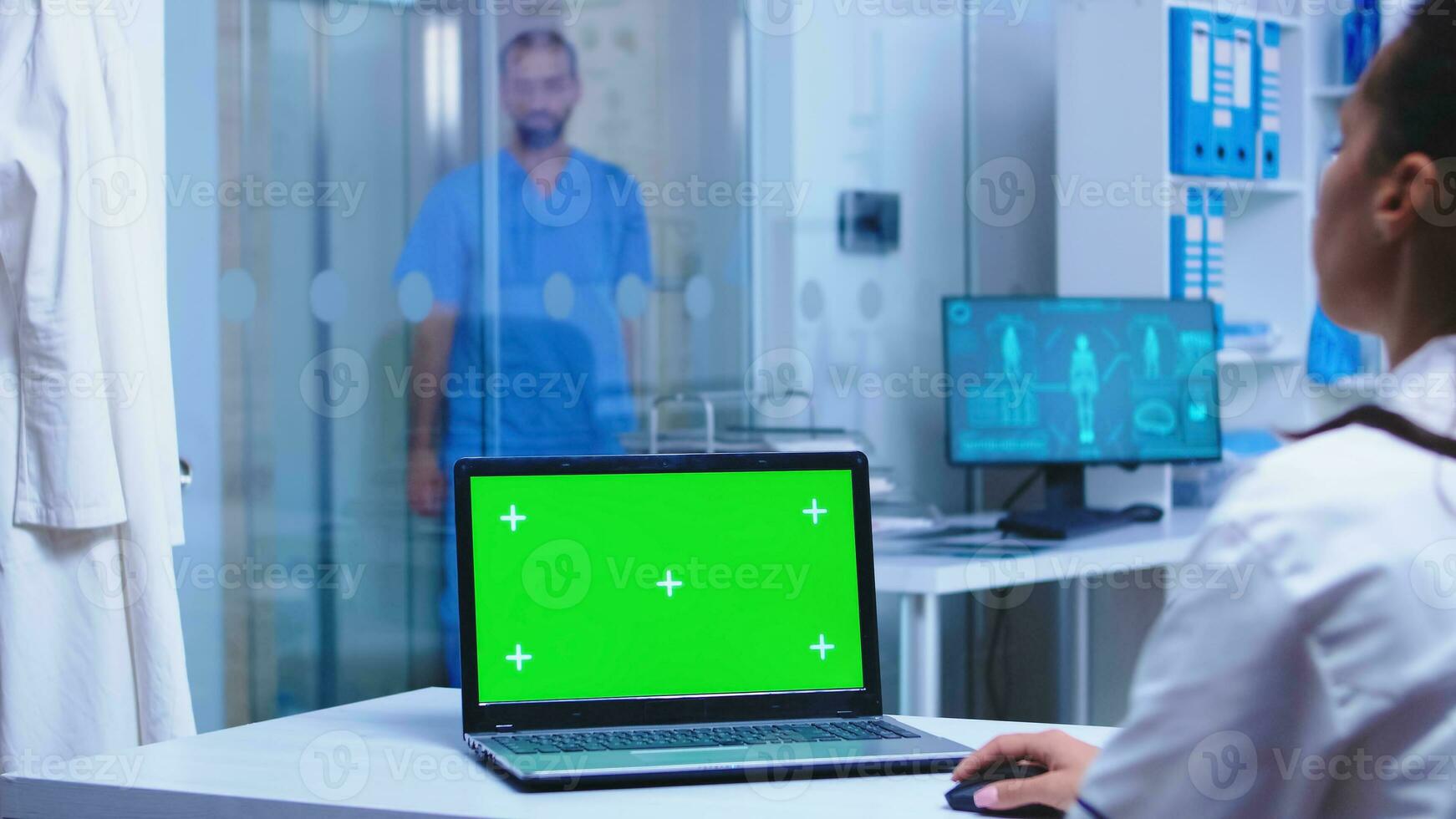 Green mockup on doctor laptop in hospital and nurse opening cabinet glass door. photo