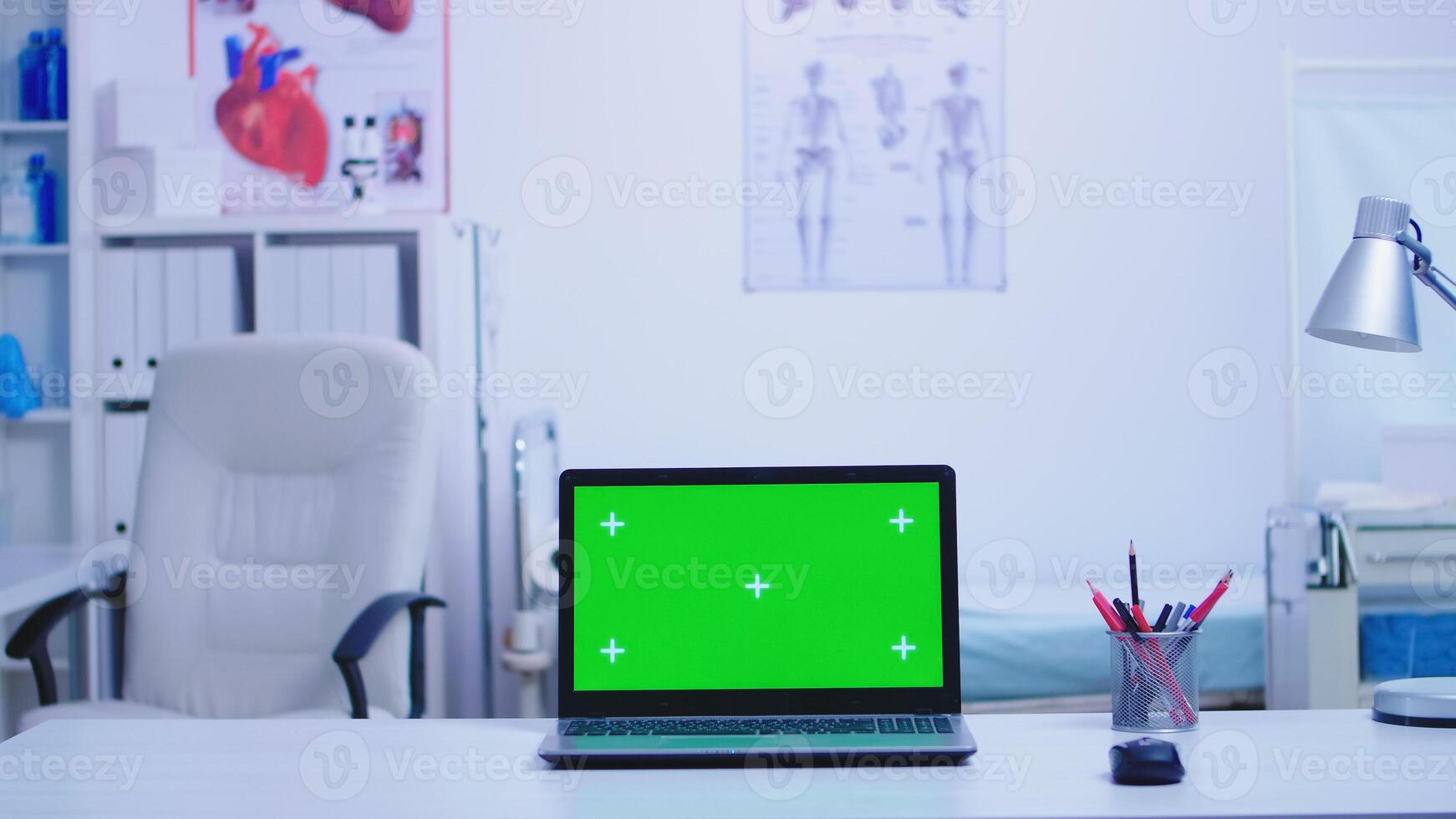 Laptop in hospital cabinet with green screen and nurse wearing blue uniform holding protection mask. Notebook with replaceable screen in medic clinic. photo