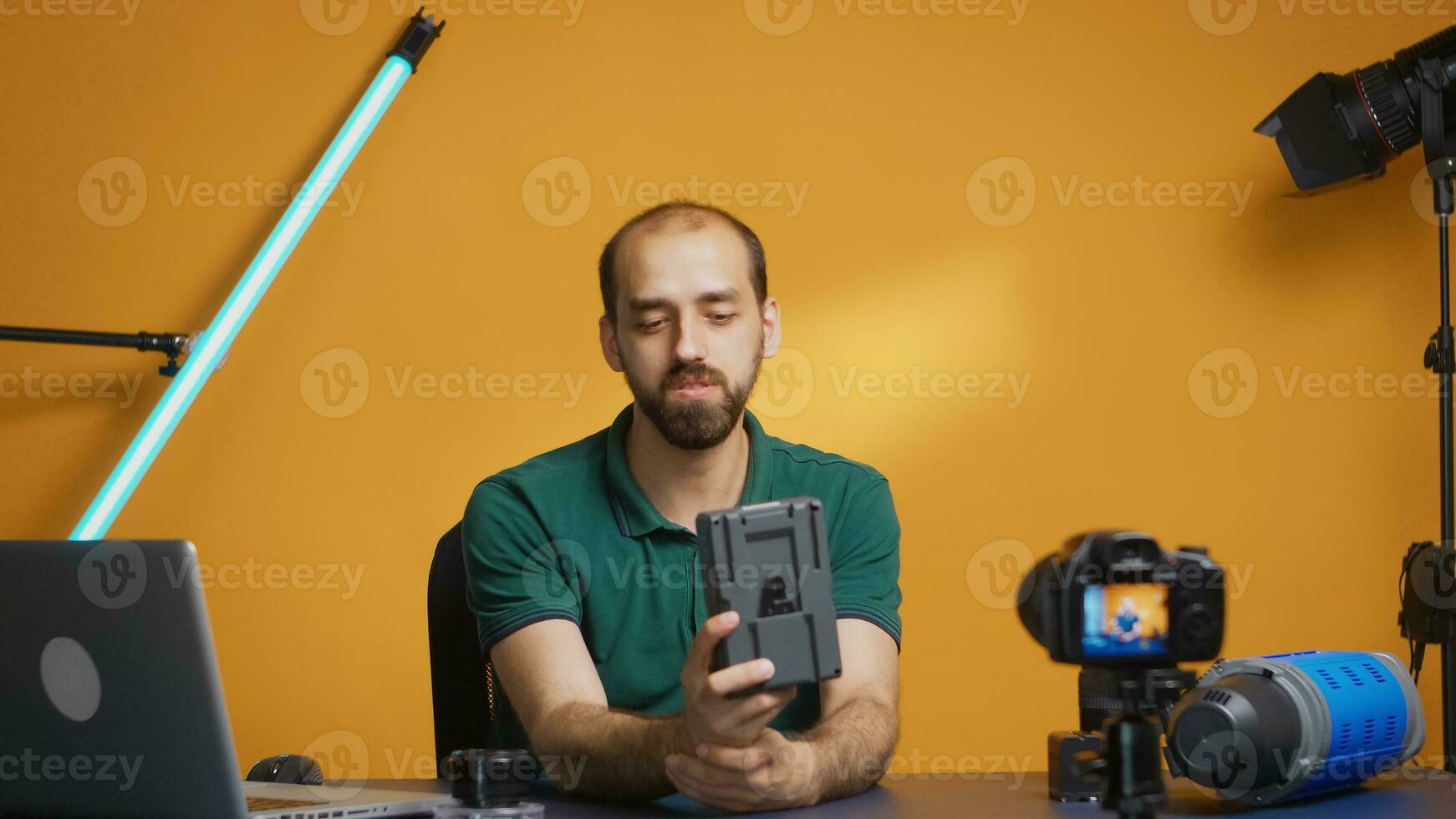 Professional videographer showing v mount battery to camera while recording vlog episode. Modern V-Lock type technology, social media star influencer online distribution photo