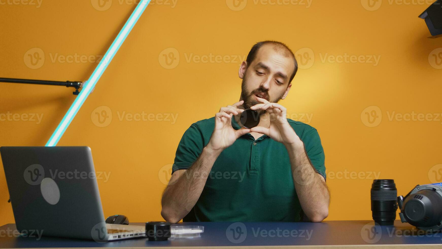 Videographer looking through nd filter while recording review for his vlog. Variable ND filter review, camera gear and equipment video. Ceator influencer social media star distributing online content photo