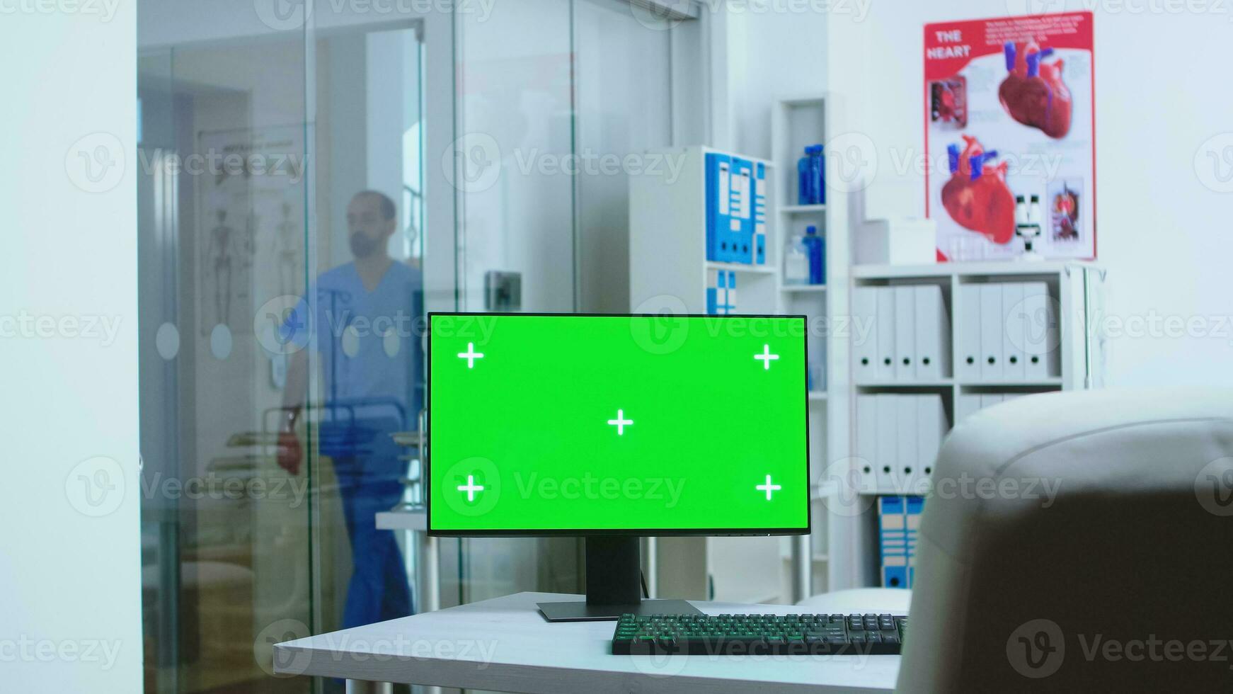 Computer with blank display in hospital cabinet and clinic personnel in the background. Desktop with copy space green screen mock up isolated available on medicine specialist in clinic cabinet. photo