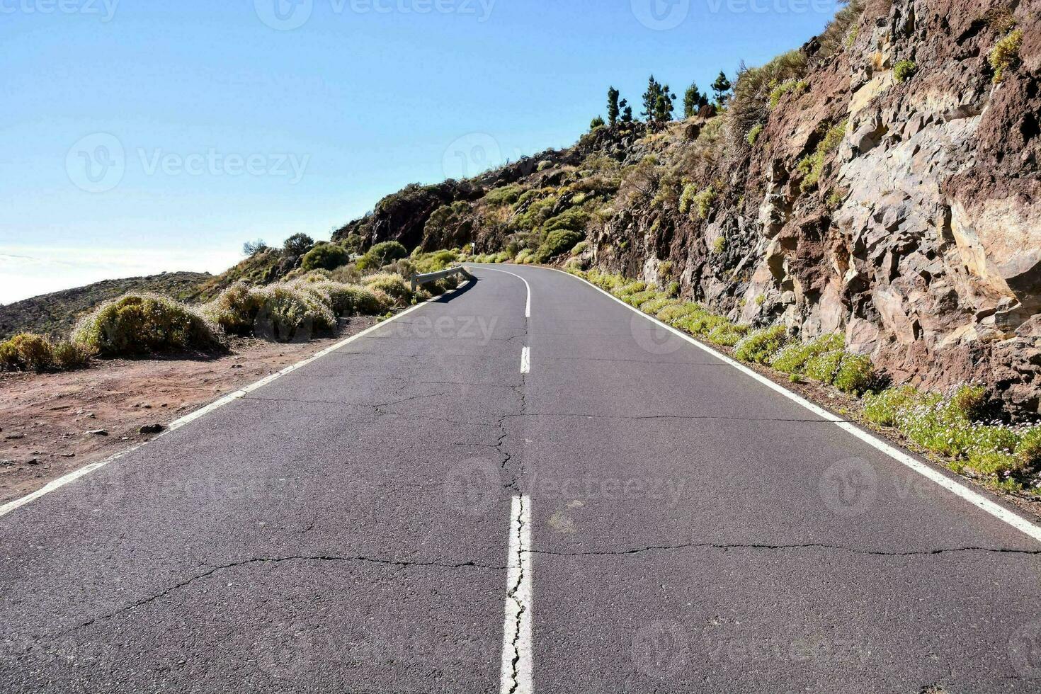 a long empty road with a mountain on one side photo