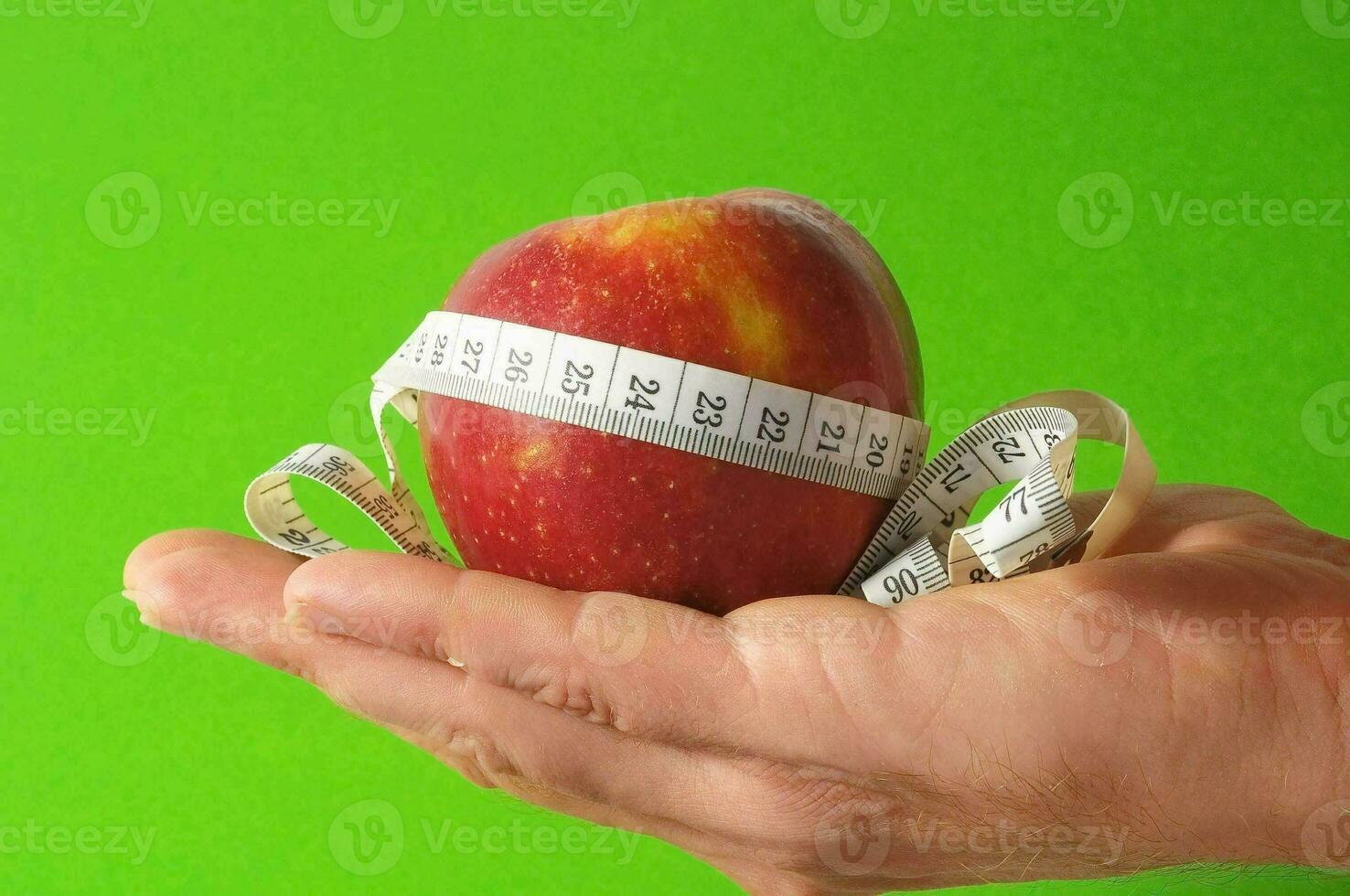 un persona participación un manzana con un medición cinta alrededor eso foto